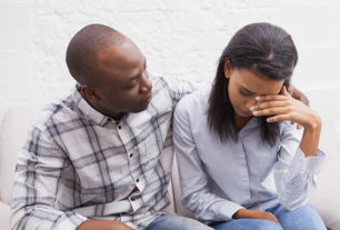 Couple sat on a couch having relationship trouble