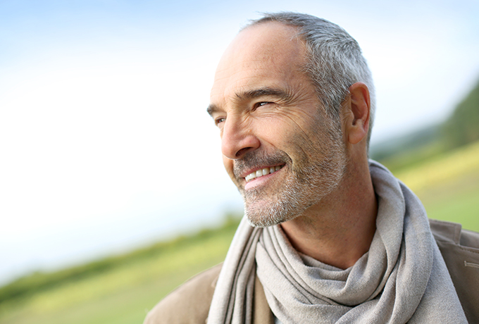 Happy middle aged man standing in a field.