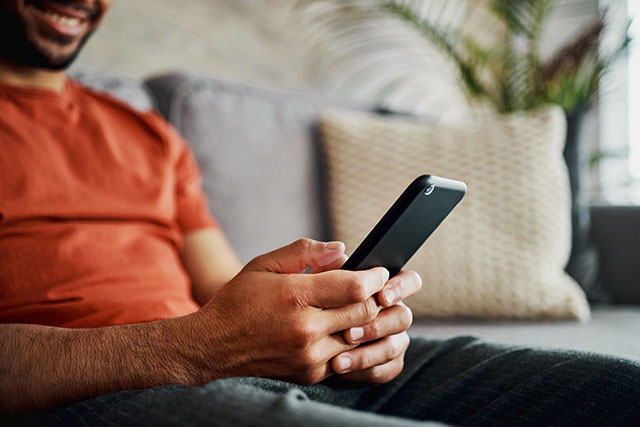 man sitting on couch using phone