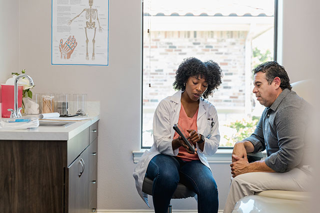 Man in doctor's office with female doctor looking at results. Why physical health is important.