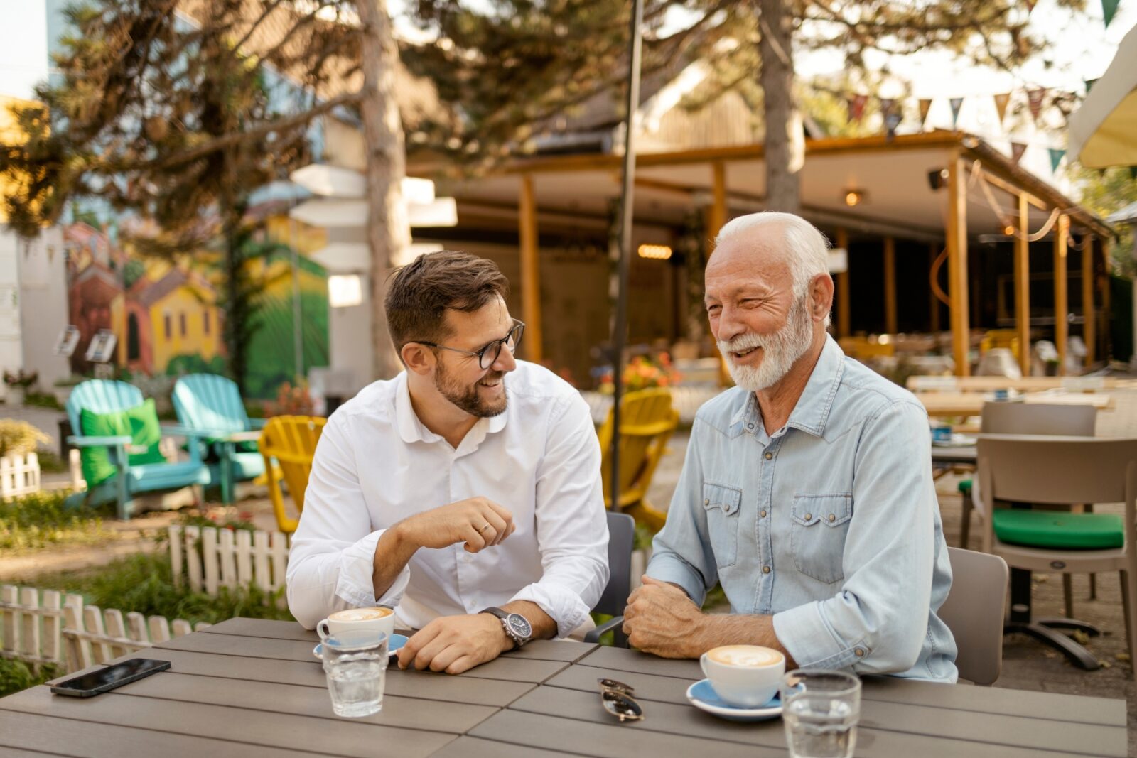 Father and son sitting outside at a cafe chatting and happily laughing