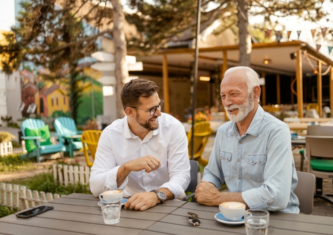 Father and son sitting outside at a cafe chatting and happily laughing